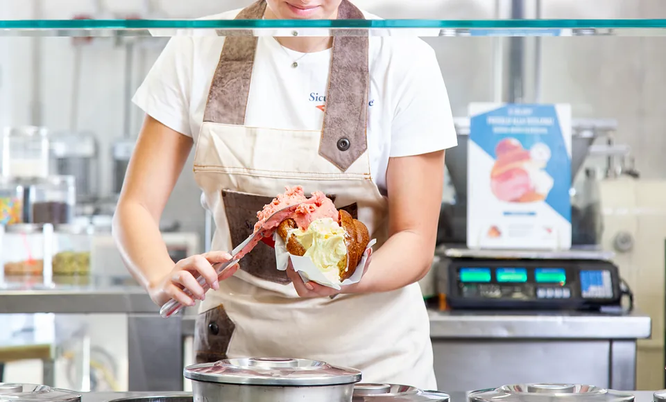 Gelatiere che farcisce una brioscia con gelato