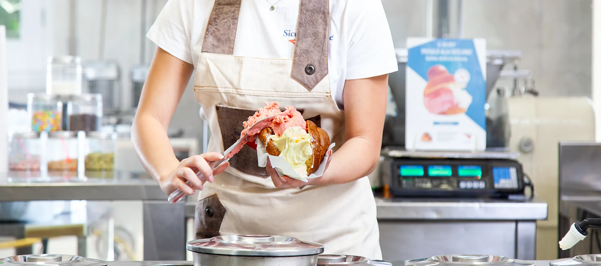 Gelatiere che farcisce una brioscia con gelato
